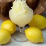 Granita al Limone servita in un bicchiere con limoni freschi