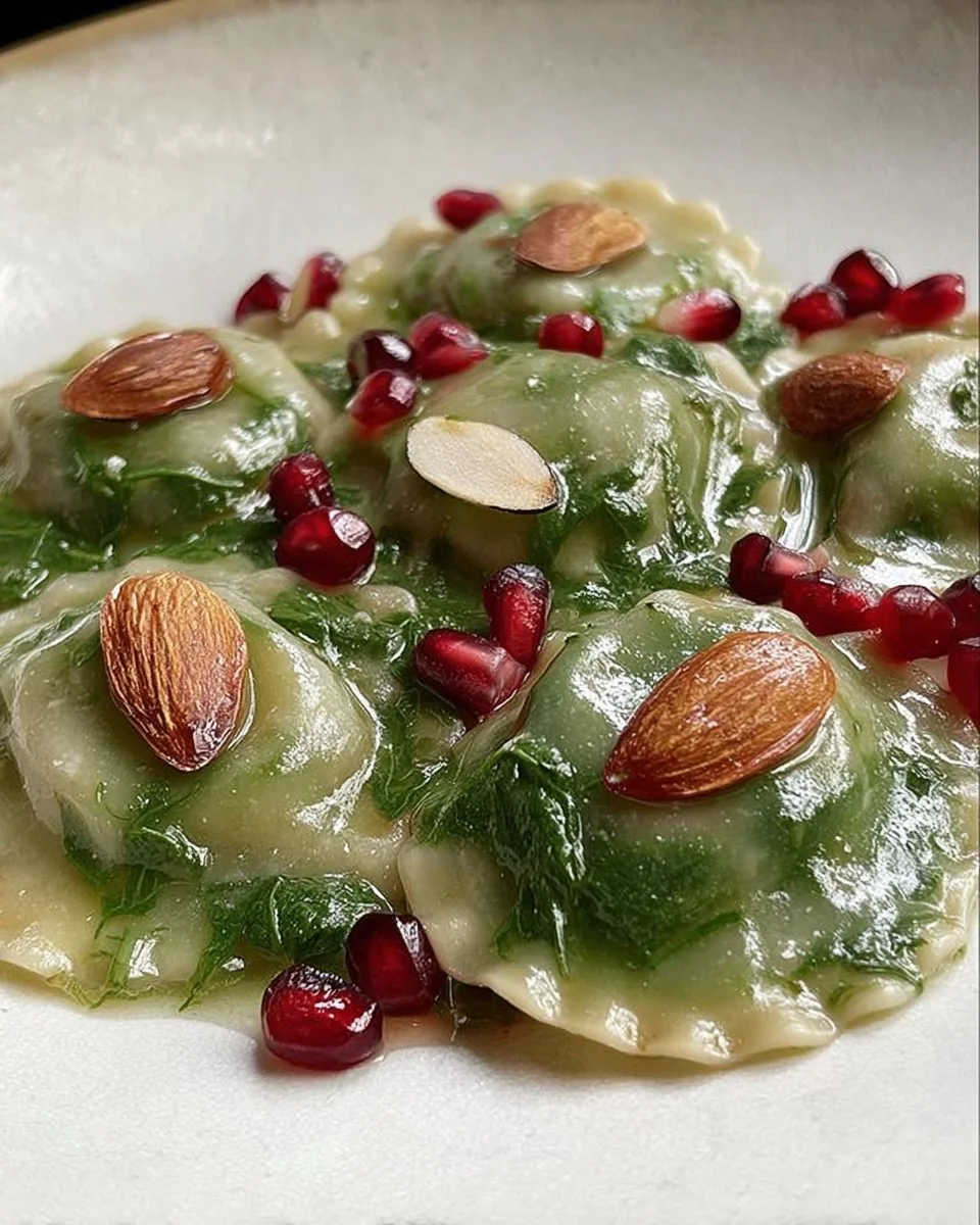 Ravioli agli spinaci ripieni di baccalà, melograno e mandorle pronti da servire.