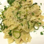 Farfalle con crema di zucchine e tonno servite in un piatto colorato