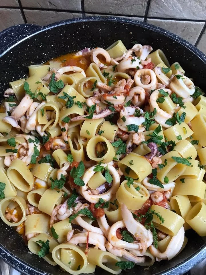 Pasta calamarata con sugo di pesce e verdure fresche.