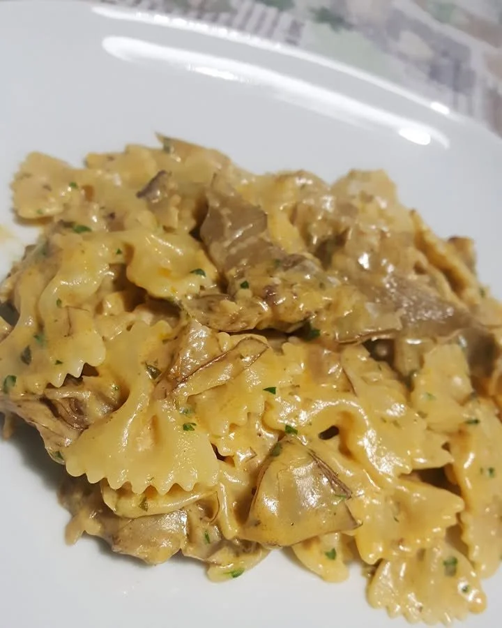 Farfalle con crema di carciofi e cuori trifolati servite in un piatto elegante