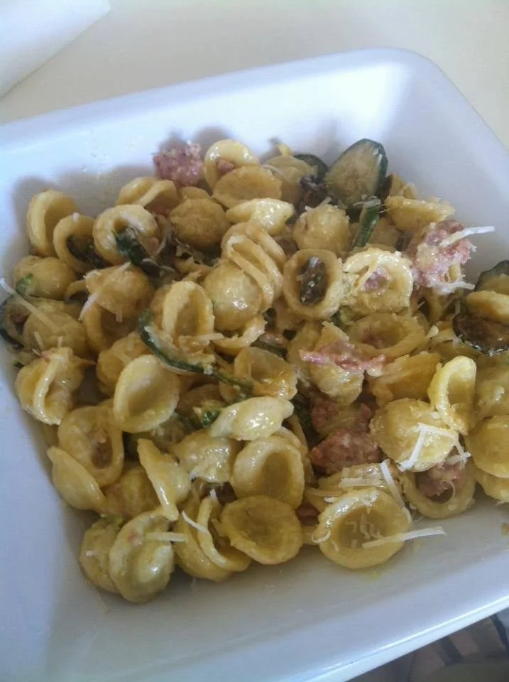 Piatto di orecchiette con zucchine, salsiccia e panna in un elegante servizio.