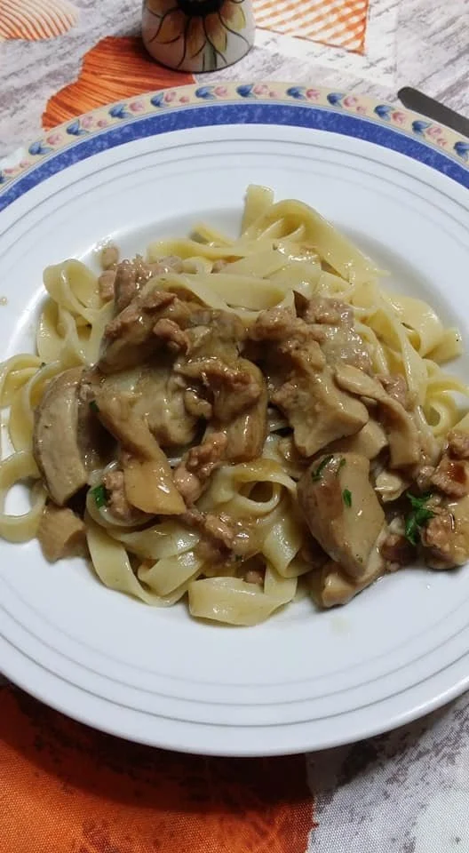 Tagliatelle ai funghi porcini e salsiccia servite su un piatto elegante