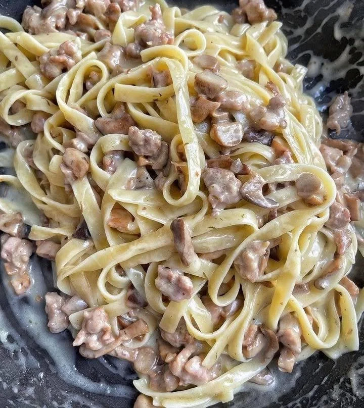 Tagliatelle con funghi e salsiccia servite in un piatto gourmet
